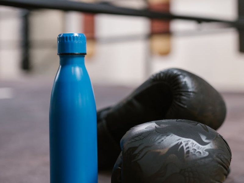 Close up of sports equipment and water bottle in a dark room.