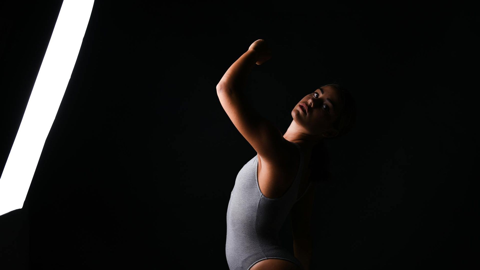 Person doing dynamic exercises in a dark atmospheric studio with lime lighting.